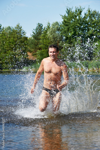 Photo: Strong man running on the water at beach Strong man running on the water at beach