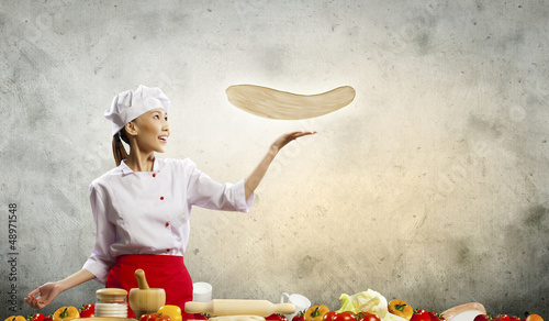 Photo: Asian female cook making pizza Asian female cook making pizza