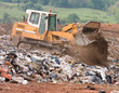 A bulldozer moving garbage on a landfill waste site