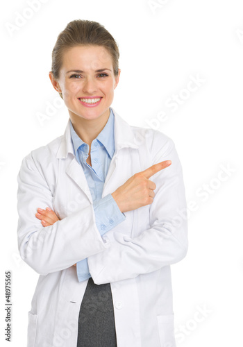 Photo: Happy medical doctor woman pointing on copy space Happy medical doctor woman pointing on copy space