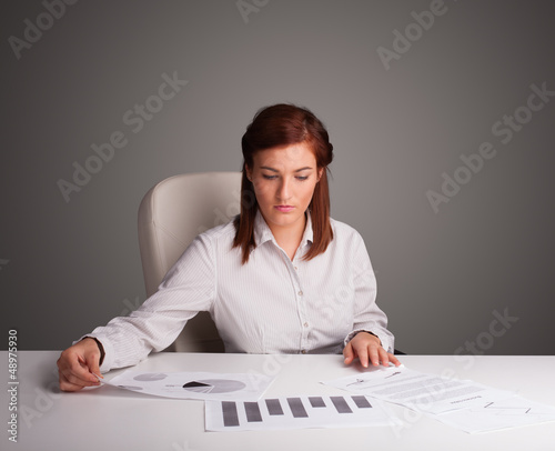 Photo: Businesswoman sitting at desk and doing paperwork Businesswoman sitting at desk and doing paperwork