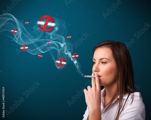 Photo: Young woman smoking dangerous cigarette with no smoking signs Young woman smoking dangerous cigarette with no smoking signs