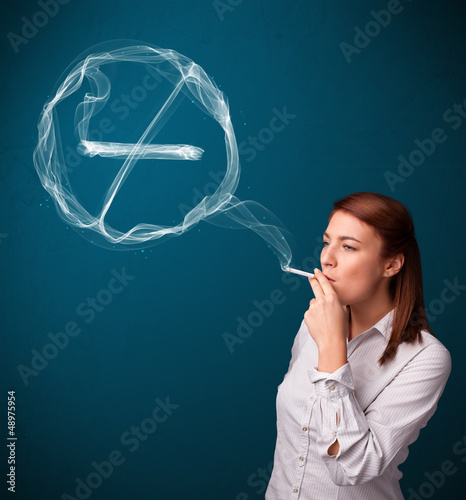 Photo: Young lady smoking unhealthy cigarette with no smoking sign Young lady smoking unhealthy cigarette with no smoking sign