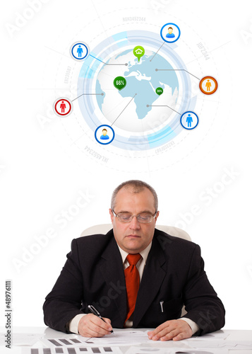 Photo: businessman sitting at desk with a globe and social icons businessman sitting at desk with a globe and social icons