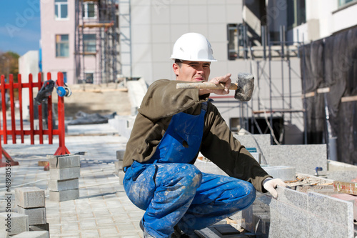Photo: Tiler at construction site pointing at something Tiler at construction site pointing at something