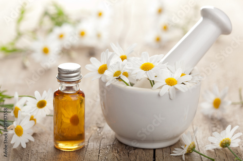 Photo: essential oil and camomile flowers in mortar essential oil and camomile flowers in mortar
