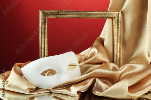 Photo: White mask, empty frame and golden silk fabric, White mask, empty frame and golden silk fabric,