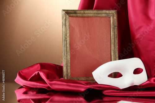 Photo: White mask, empty frame and golden silk fabric, White mask, empty frame and golden silk fabric,