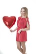 Beautiful woman holding red heart balloon over white background.