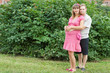 a happy young pregnant woman with her husband rests in a park