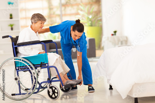 Photo: young caregiver helping elderly woman on wheelchair young caregiver helping elderly woman on wheelchair