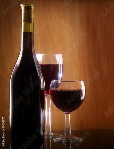 Photo: Red wine glass and Bottle on a wooden background Red wine glass and Bottle on a wooden background