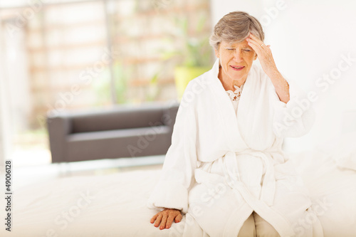 Photo: senior woman sitting on bed and having headache senior woman sitting on bed and having headache