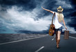 Young woman with guitar on the road and her vintage baggage