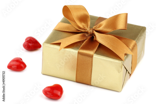Photo: Valentine day's gift wrapped in golden paper with bow and hearts Valentine day's gift wrapped in golden paper with bow and hearts