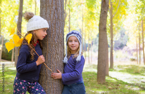 Photo: Autumn sister kid girls playing in forest trunk outdoor Autumn sister kid girls playing in forest trunk outdoor