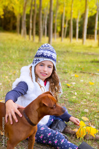 Photo: Autumn girl in poplar tree forest playing with dog Autumn girl in poplar tree forest playing with dog