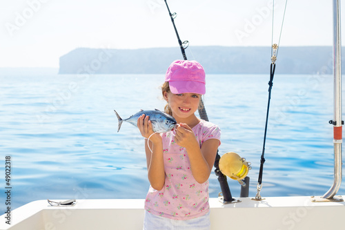 Photo: child little girl fishing in boat holding little tunny fish catc child little girl fishing in boat holding little tunny fish catc