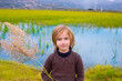 Blond kid girl outdoor holding spike in wetlands lake