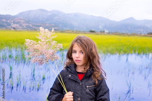 Photo: Brunette kid girl outdoor holding spike in wetlands lake Brunette kid girl outdoor holding spike in wetlands lake