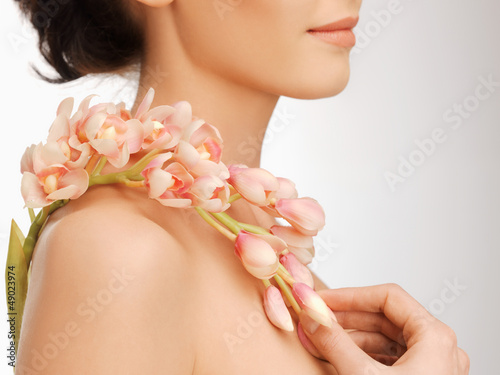 Photo: woman's shoulder and hands holding orchid flower woman's shoulder and hands holding orchid flower