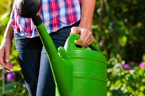 Photo: Woman in garden with watering can in hand Woman in garden with watering can in hand