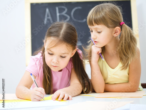 Photo: Little girls are writing using a pen Little girls are writing using a pen