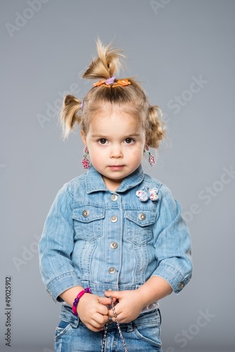 Photo: Funny little girl isolated on grey Funny little girl isolated on grey
