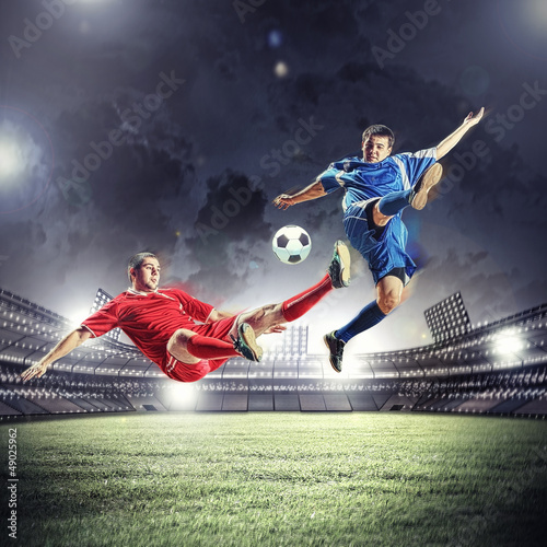 Photo: two football players striking the ball two football players striking the ball