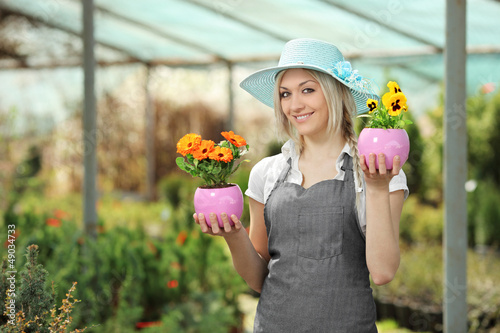 Photo: Female gardener holding flower pots in a garden Female gardener holding flower pots in a garden