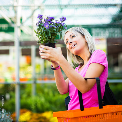 Photo: Young woman buying flowers at a garden center Young woman buying flowers at a garden center