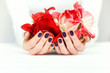 Hands with beautiful manicure holding bright flowers on white