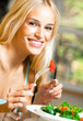 Happy smiling young woman eating salad