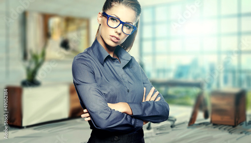 Photo: Closeup portrait of pretty cheerful business woman in an office Closeup portrait of pretty cheerful business woman in an office