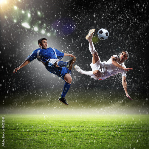 Photo: two football players striking the ball two football players striking the ball