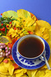 Cup of tea on autumn leaves on blue background