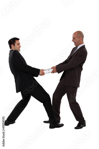 Photo: Two businessman pulling in different directions Two businessman pulling in different directions