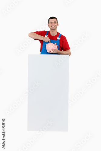 Photo: Worker with a piggy bank and a board for message Worker with a piggy bank and a board for message