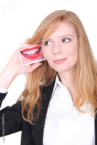Photo: Young woman holding a photo of a mouth next to her ear Young woman holding a photo of a mouth next to her ear