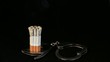 smoldering cigarette in handcuffs on black background, Timelapse