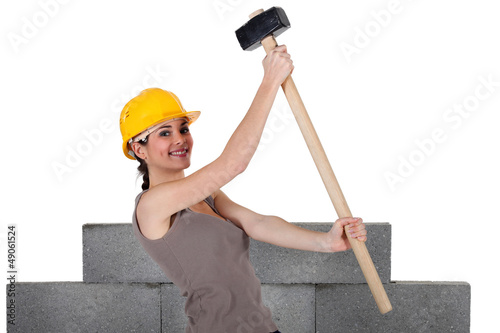 Photo: Woman lifting sledge-hammer in front of unfinished wall Woman lifting sledge-hammer in front of unfinished wall