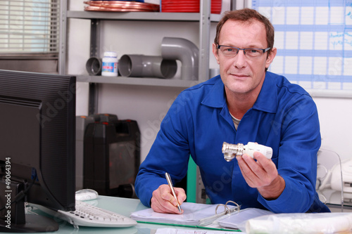 Photo: Plumber at a counter with a radiator valve Plumber at a counter with a radiator valve