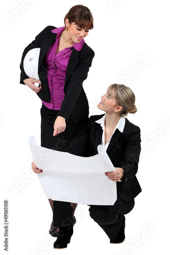 Photo: two real estate businesswomen looking at a blueprint two real estate businesswomen looking at a blueprint