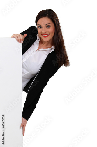 Photo: Brunette woman peeking behind a white panel Brunette woman peeking behind a white panel