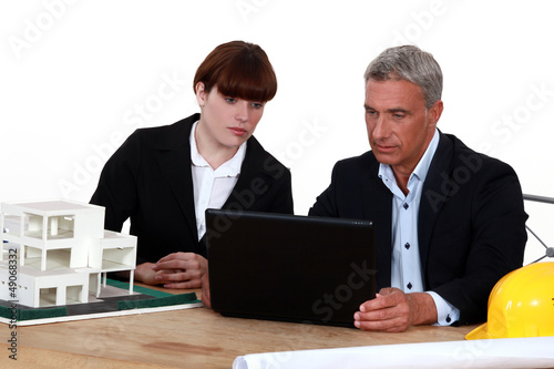 Photo: Architect and colleague sat by model housing Architect and colleague sat by model housing