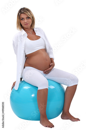 Photo: Pregnant woman holding her tummy and sitting on an ball Pregnant woman holding her tummy and sitting on an ball