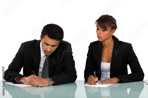 Photo: Two businesspeople writing at a desk Two businesspeople writing at a desk