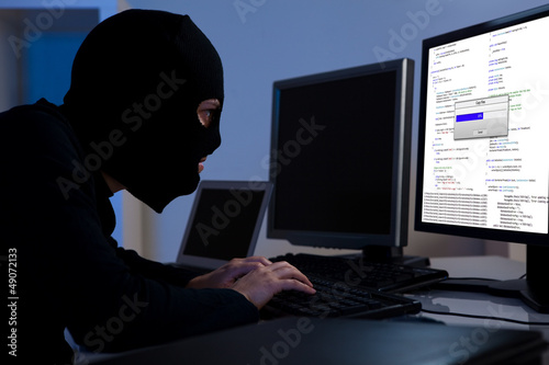 Photo: Hacker downloading information off a computer Hacker downloading information off a computer