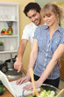 a couple watching a computer in the kitchen
