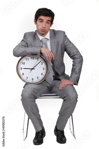 Photo: Businessman bored with alarm clock Businessman bored with alarm clock